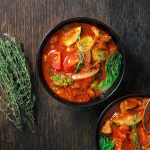 Zuppa rustica con datterini confit, verdure e timo in ciotola scura