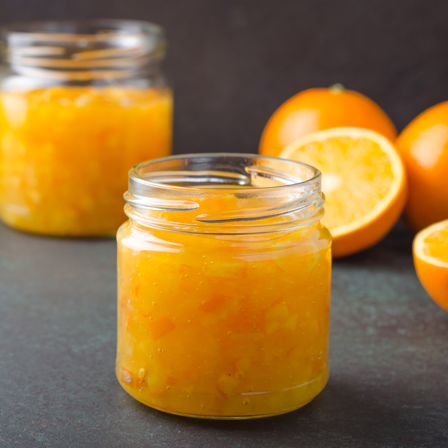 Vasetti di composta biologica di arance bionde con agrumi freschi sullo sfondo.